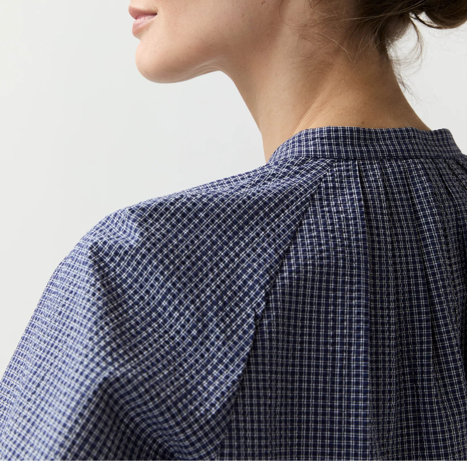 Woman wearing a blue checkered shirt against a light background