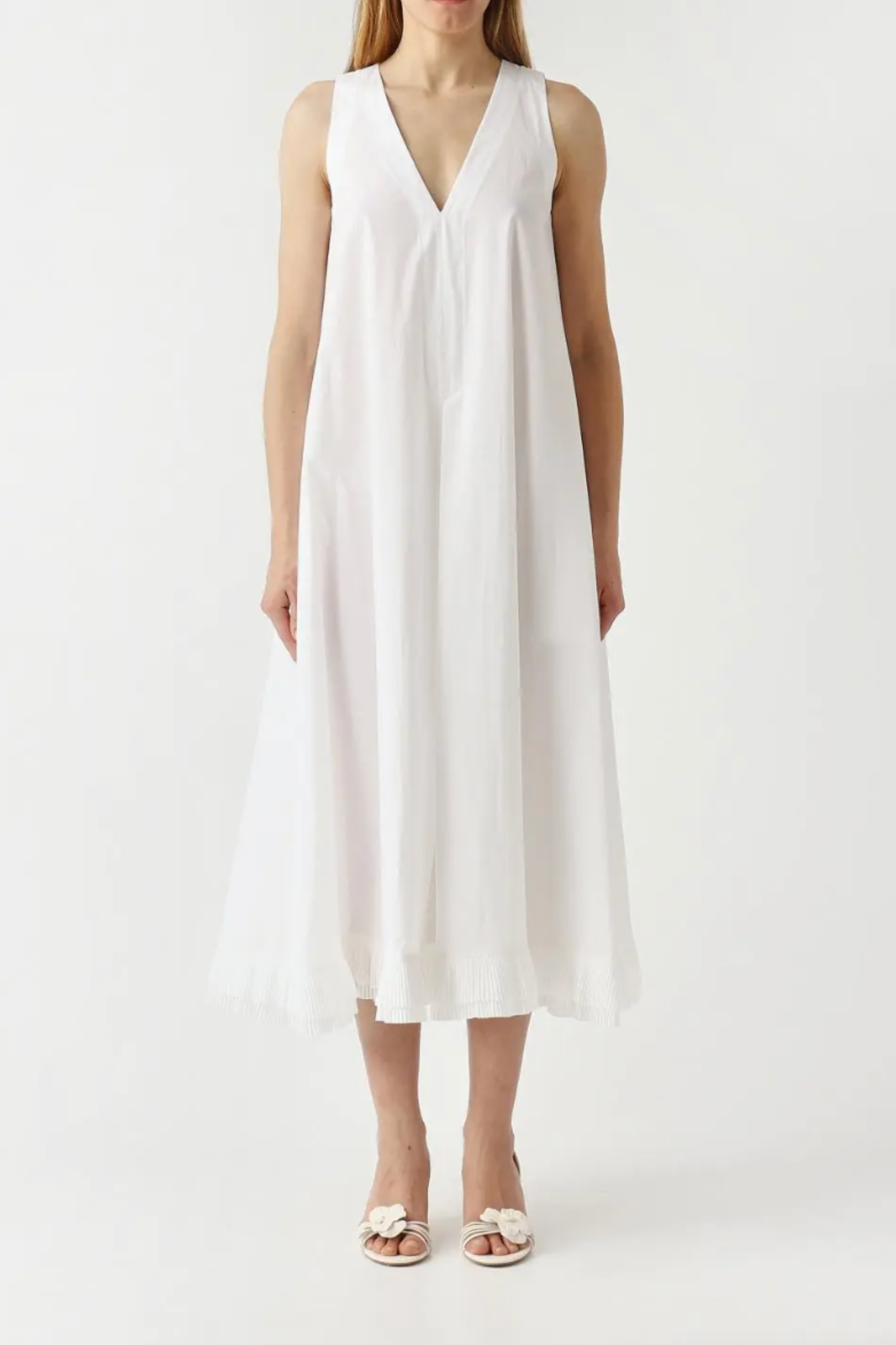 Woman wearing a white sleeveless dress on a plain background