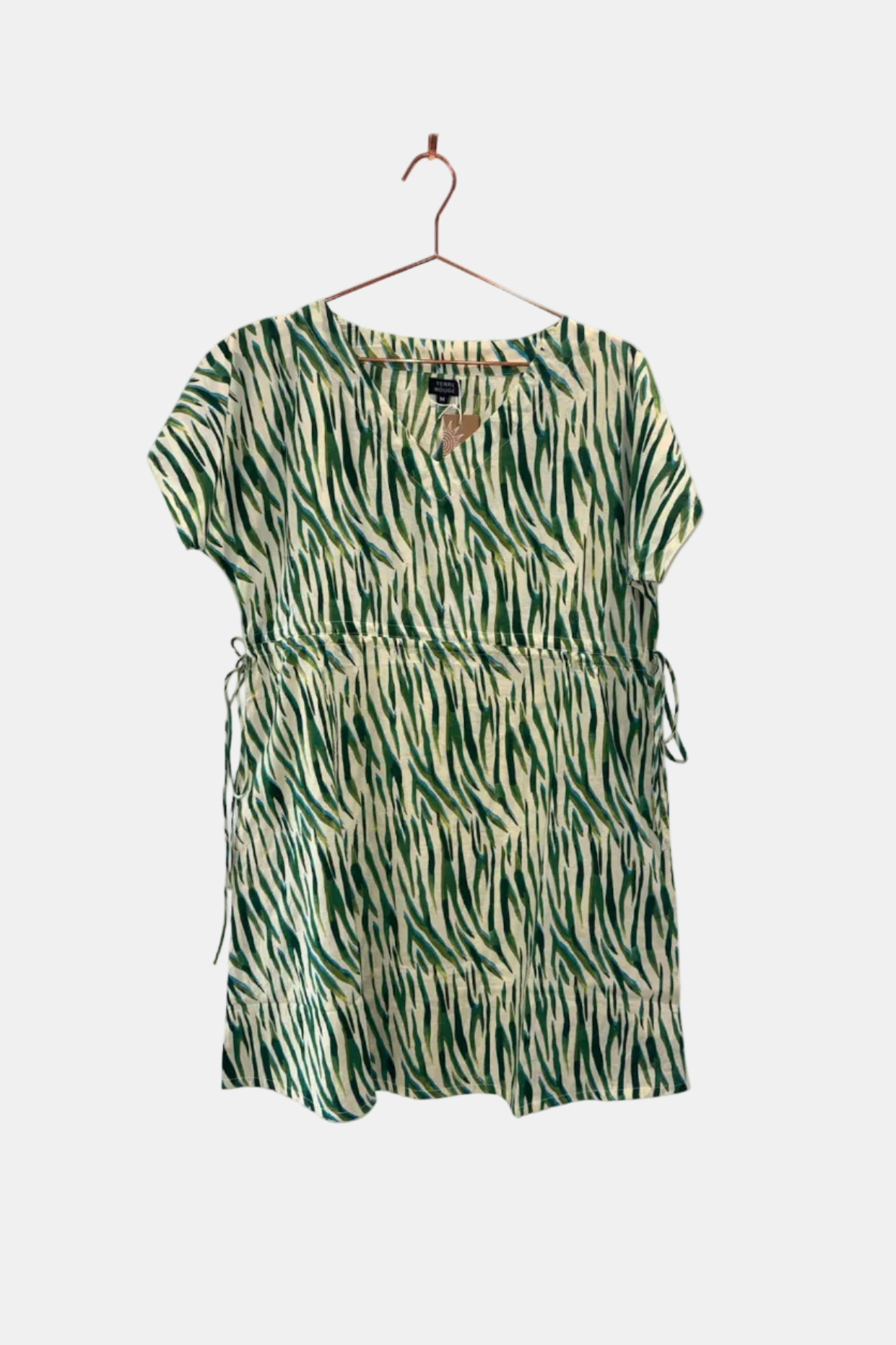 Green and beige patterned dress on a hanger against a white background