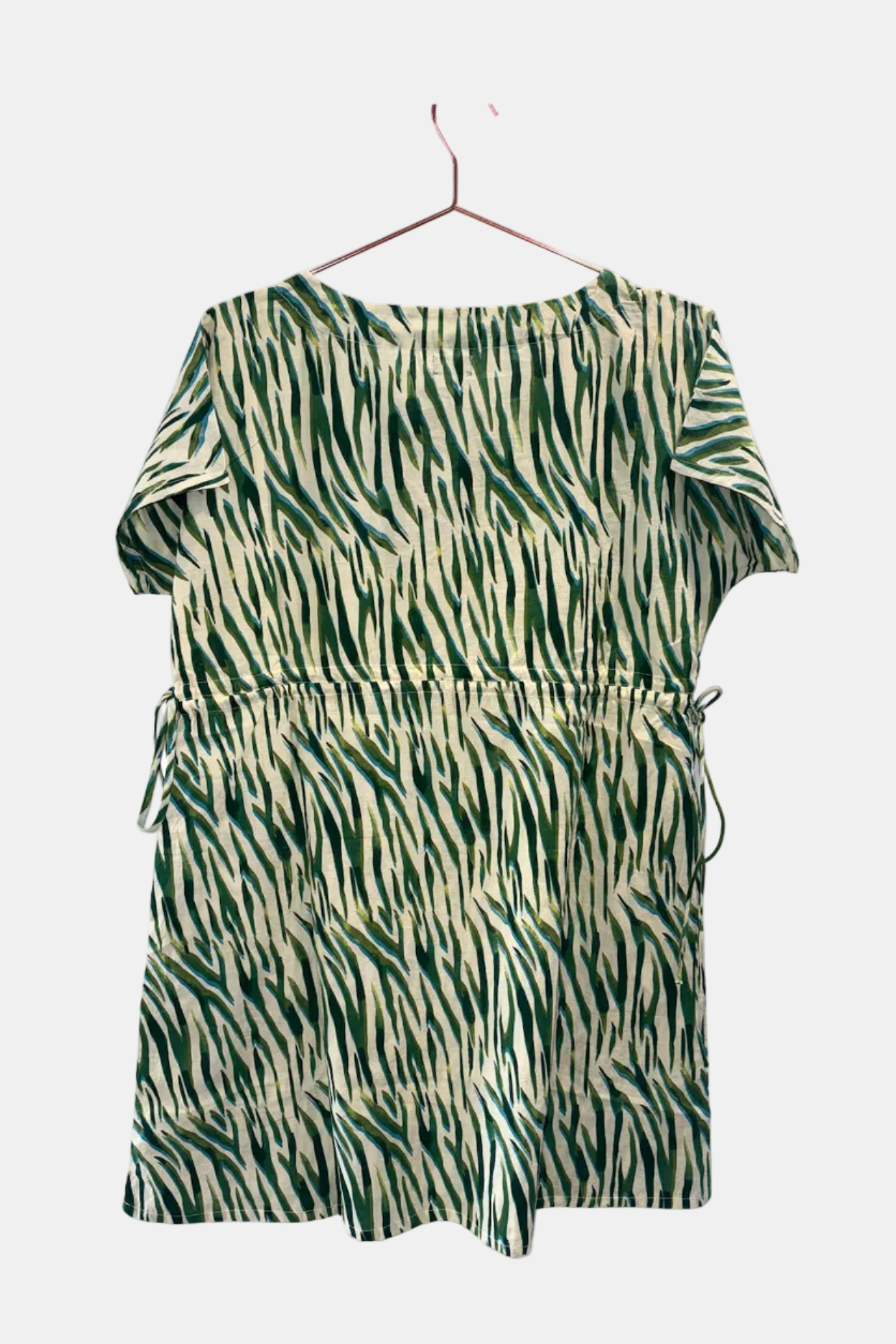 Green and beige patterned dress on a hanger against a white background