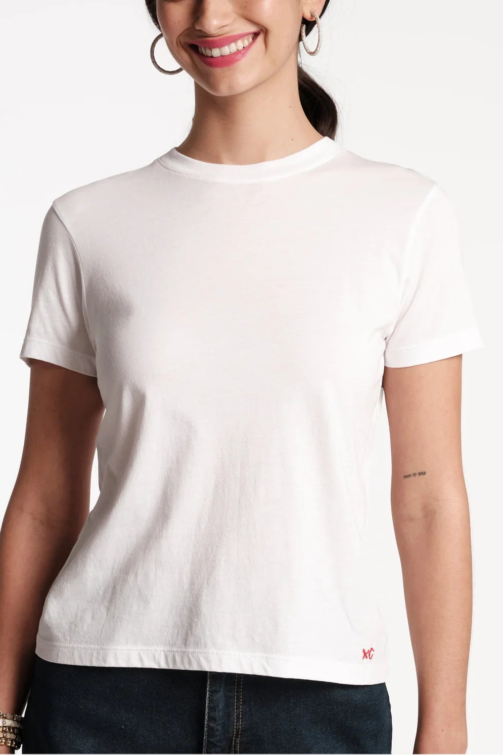 Woman wearing a plain white t-shirt with a small logo on a white background