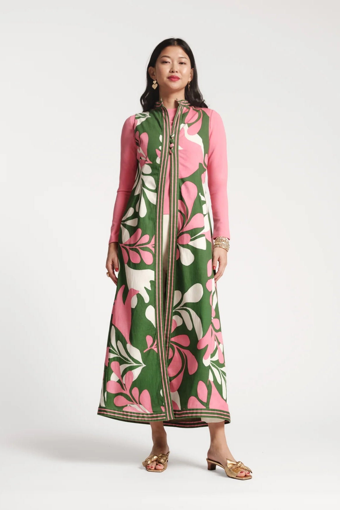 Woman wearing a long, patterned dress with pink and green floral design on a white background