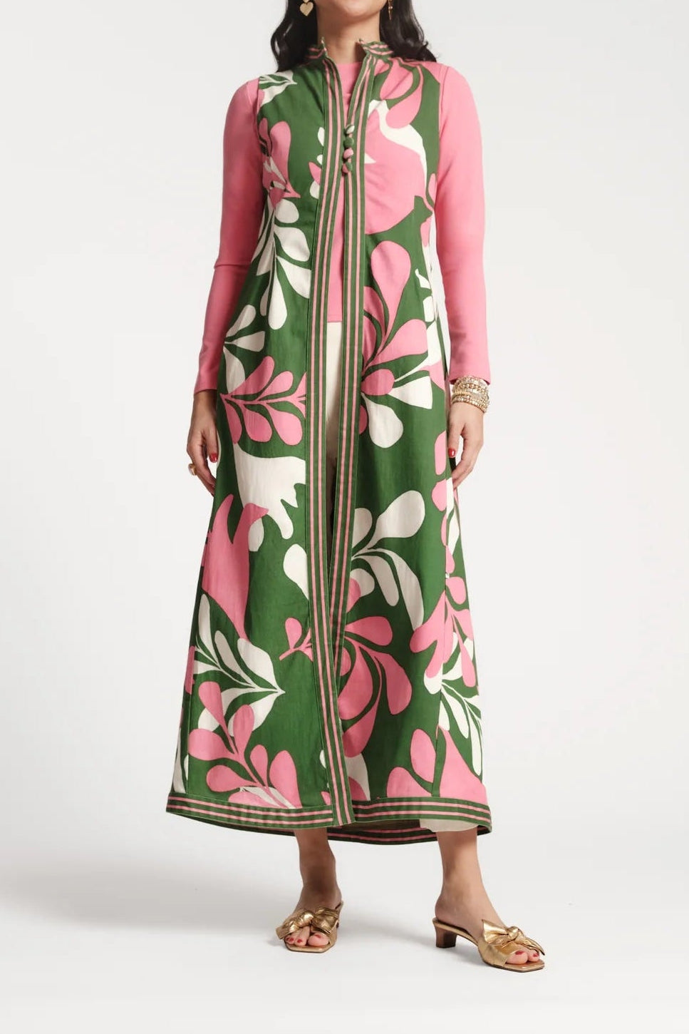 Woman wearing a long, patterned dress with pink and green floral design on a white background