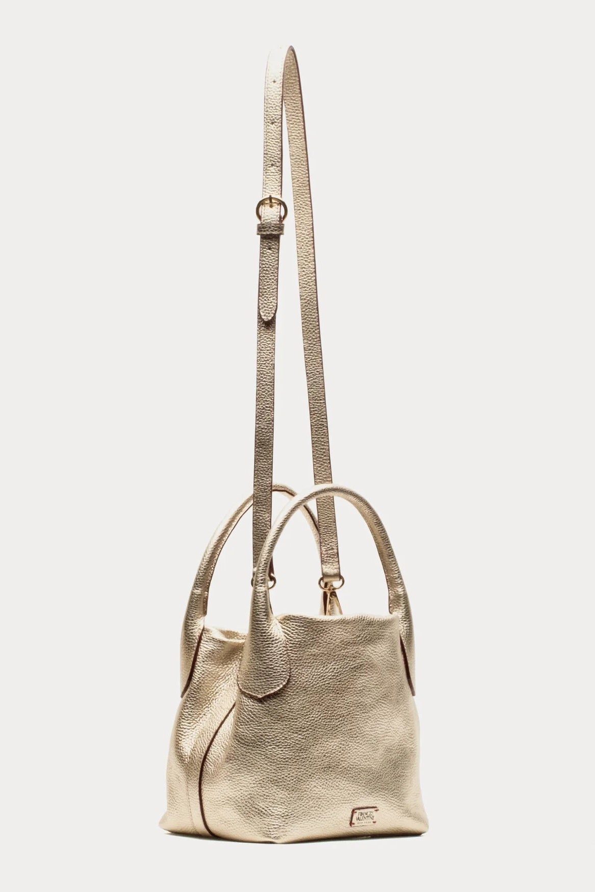 A metallic champagne-gold leather shoulder bag with a long adjustable strap, dual top handles, and a small gold logo plaque on the bottom right, shown against a plain light gray background.