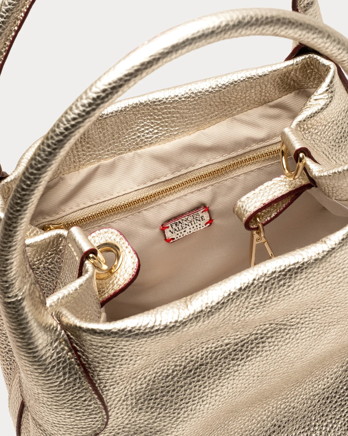 Close-up of a gold handbag with a visible brand logo on a light background