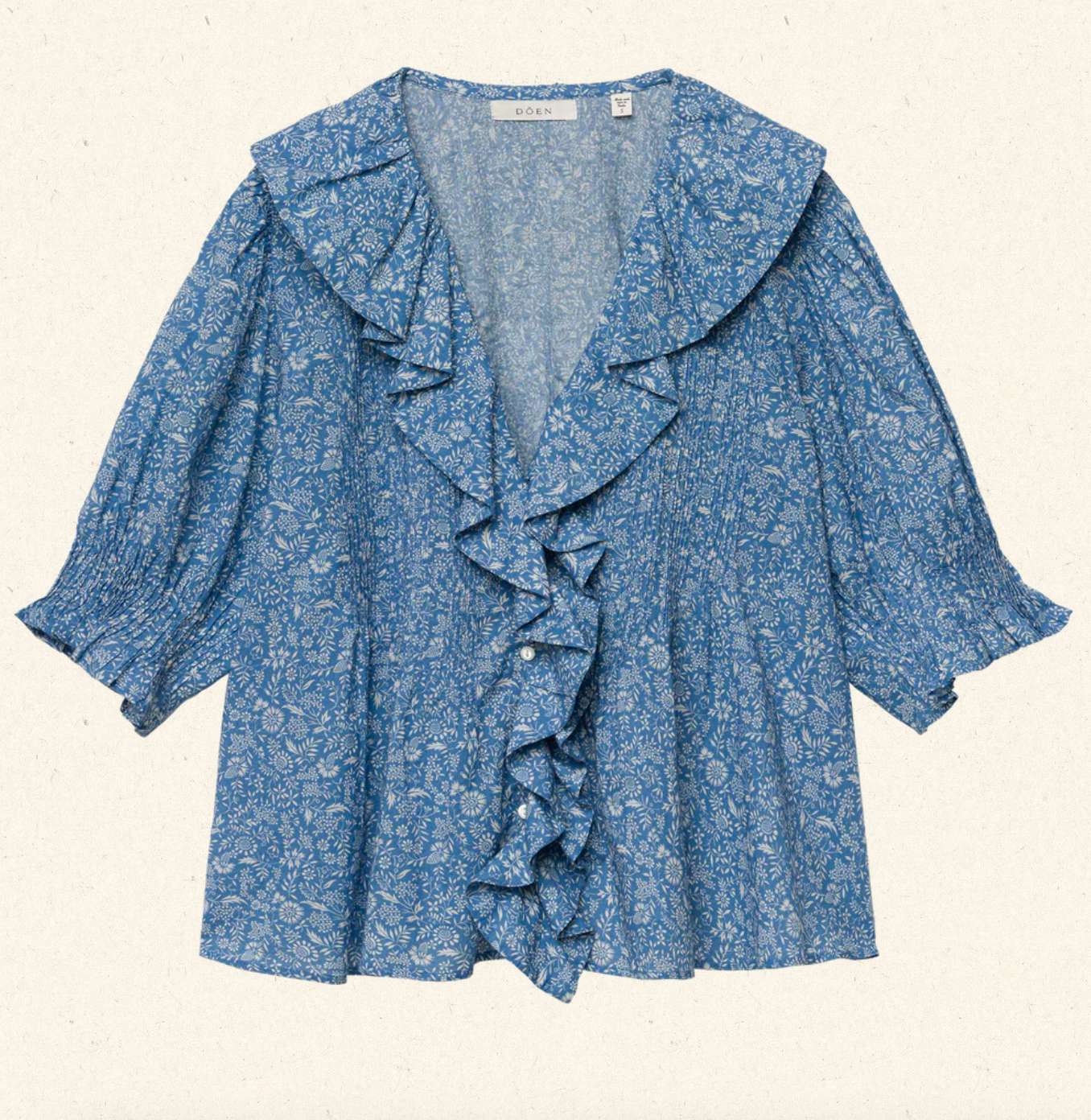 Blue floral blouse with ruffled details on a beige background