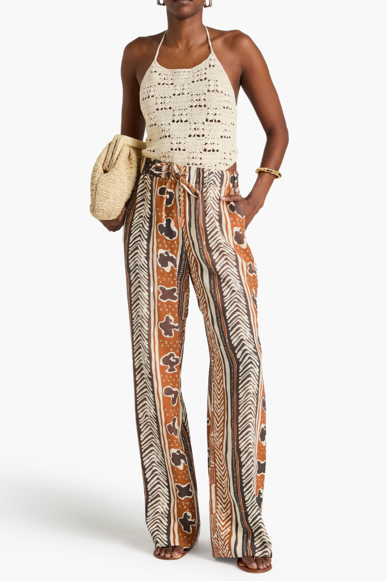 Woman wearing a patterned top and wide-leg pants with a white background