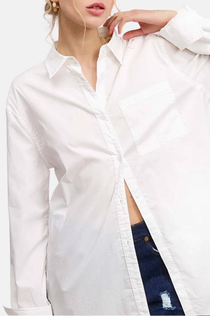 A woman wearing an oversized white long-sleeve button-up shirt with a chest pocket, paired with dark blue jeans, posed against a white background with light pink graphic accents.