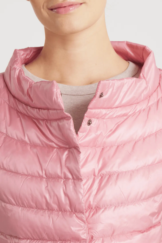 Close-up of a person wearing a shiny light pink puffer jacket with a high collar and snap-button front over a light gray shirt.