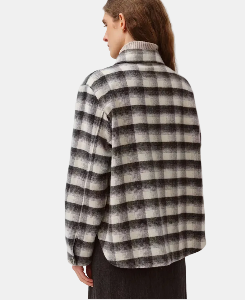 A model shown from the back wearing a long-sleeve plaid sweater with a high ribbed mock neck. The sweater features a checkered pattern in black, gray, and off-white.