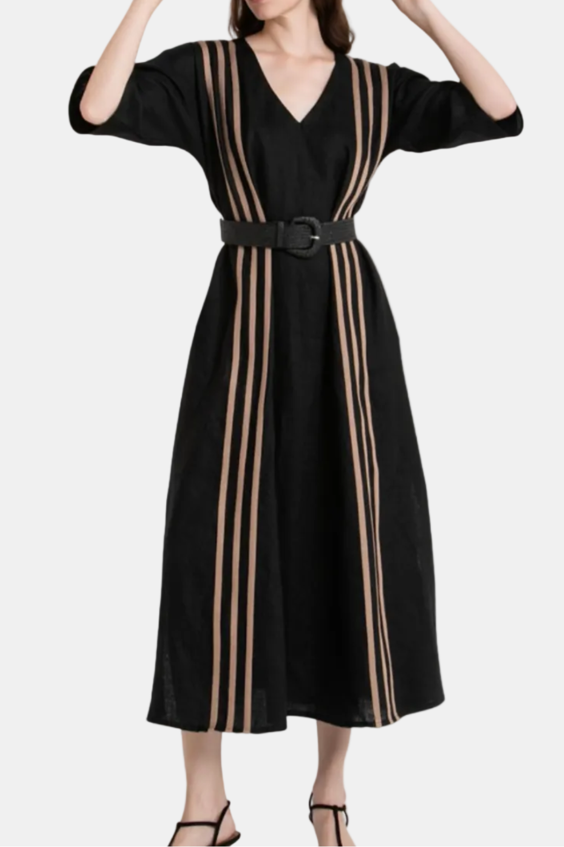 Woman wearing a black dress with beige stripes and a wide-brimmed hat on a white background