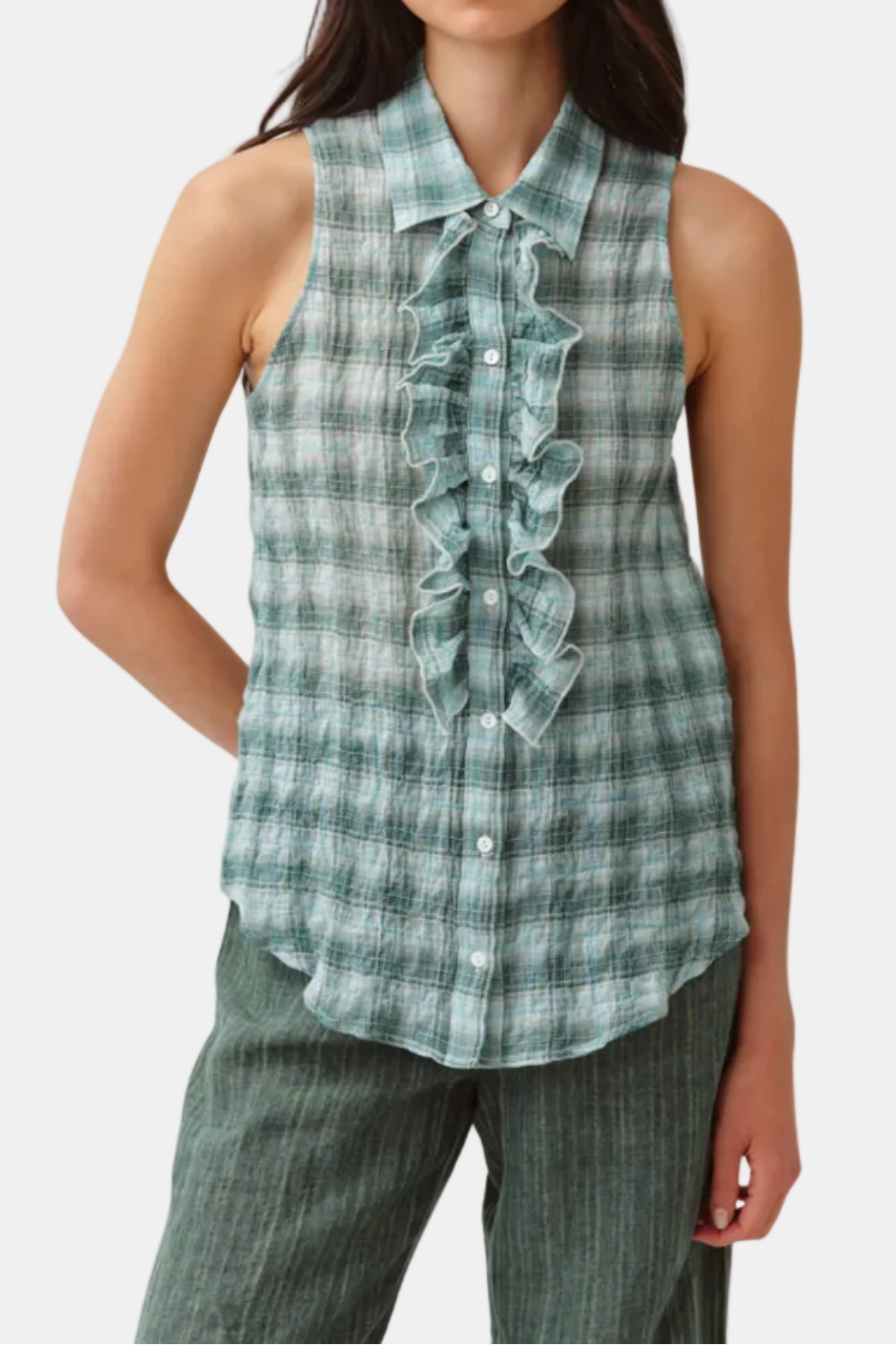 Woman wearing a sleeveless plaid shirt with ruffles on a white background