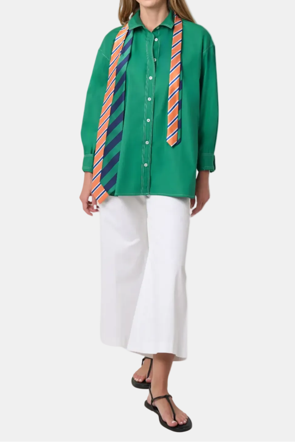 Woman wearing a green shirt with colorful striped ties and white pants on a white background