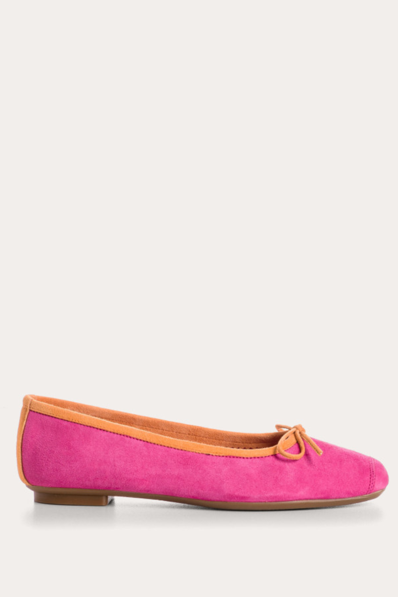 Pink suede ballerina shoe with brown trim on a white background