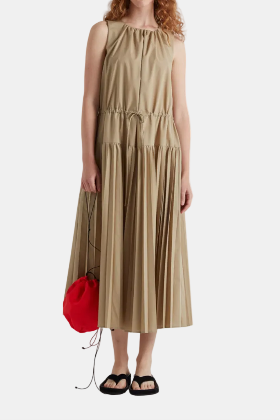 Woman wearing a beige dress holding a red bag on a white background