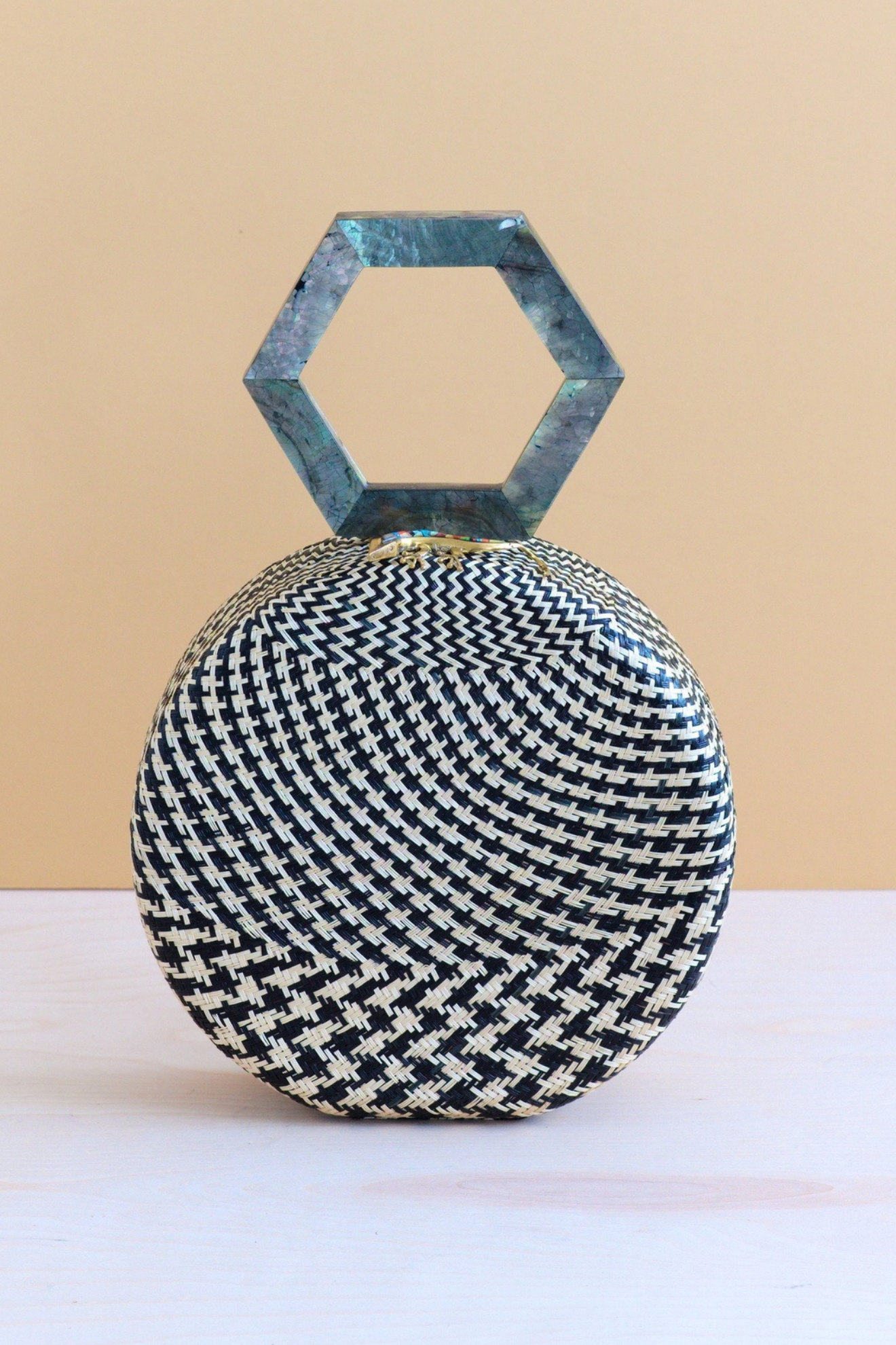 Woven handbag with a geometric handle on a beige background