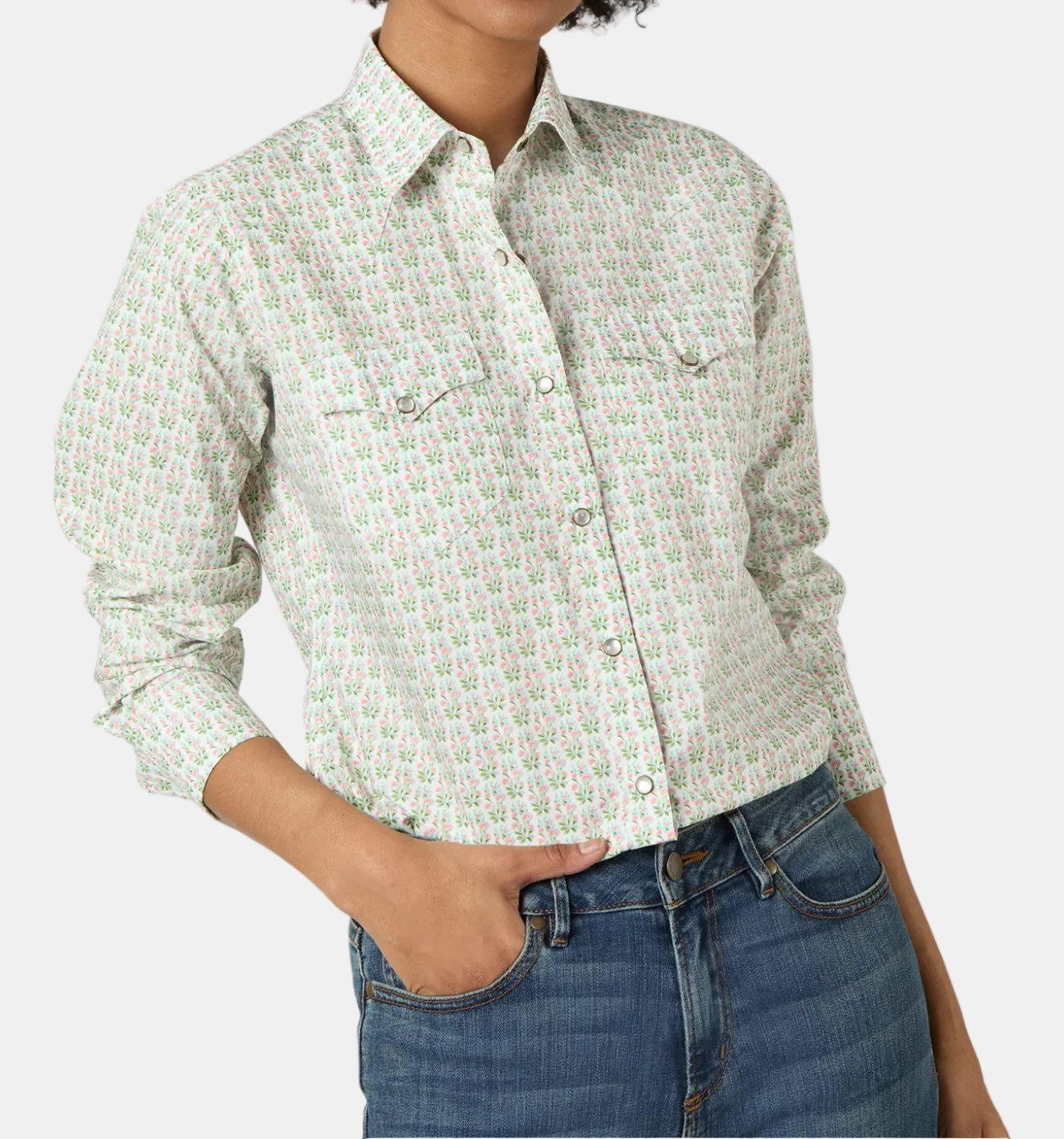 A woman wearing a green and white floral print Western-style shirt with long sleeves, pearl snaps, and twin front pockets.