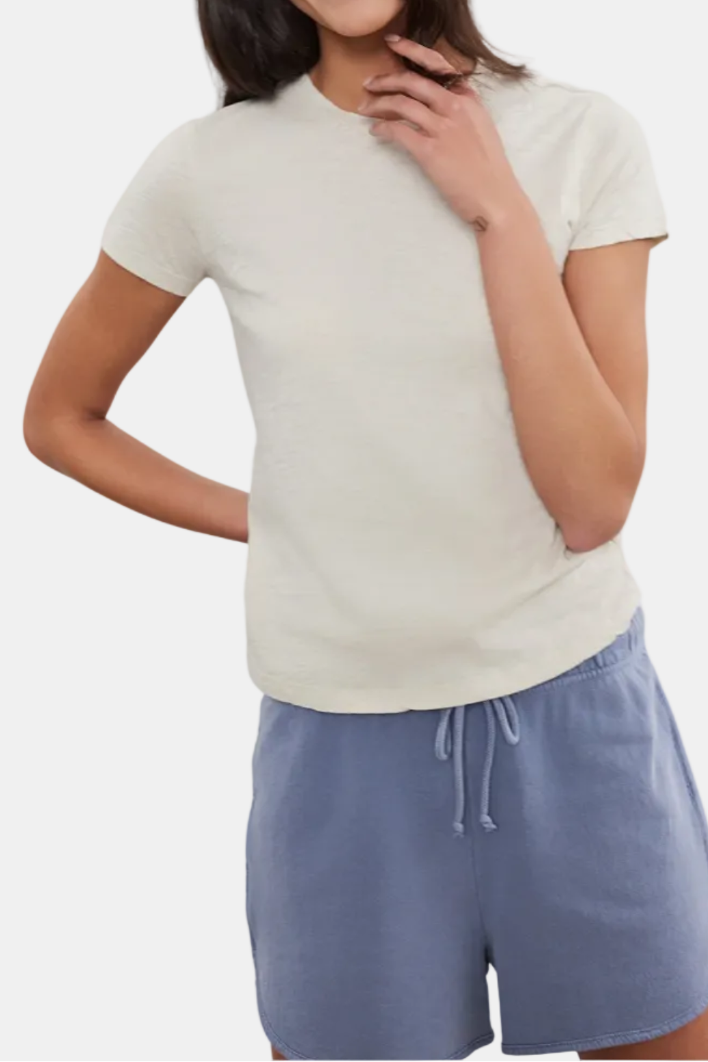 A woman wearing a short sleeve beige t-shirt and blue shorts.
