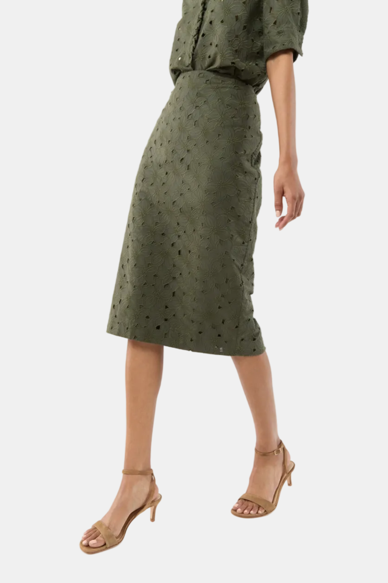 Person wearing a green skirt with cut-out pattern on a white background
