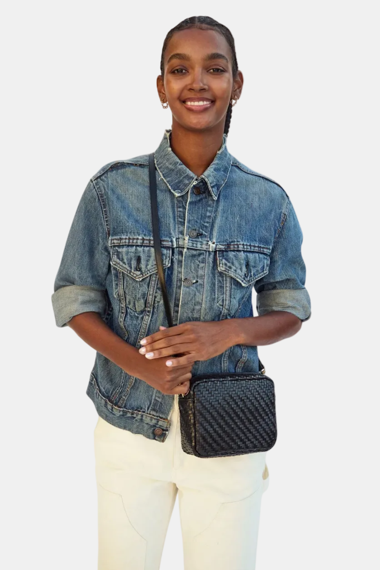 Person wearing a denim jacket holding a black textured bag on a white background