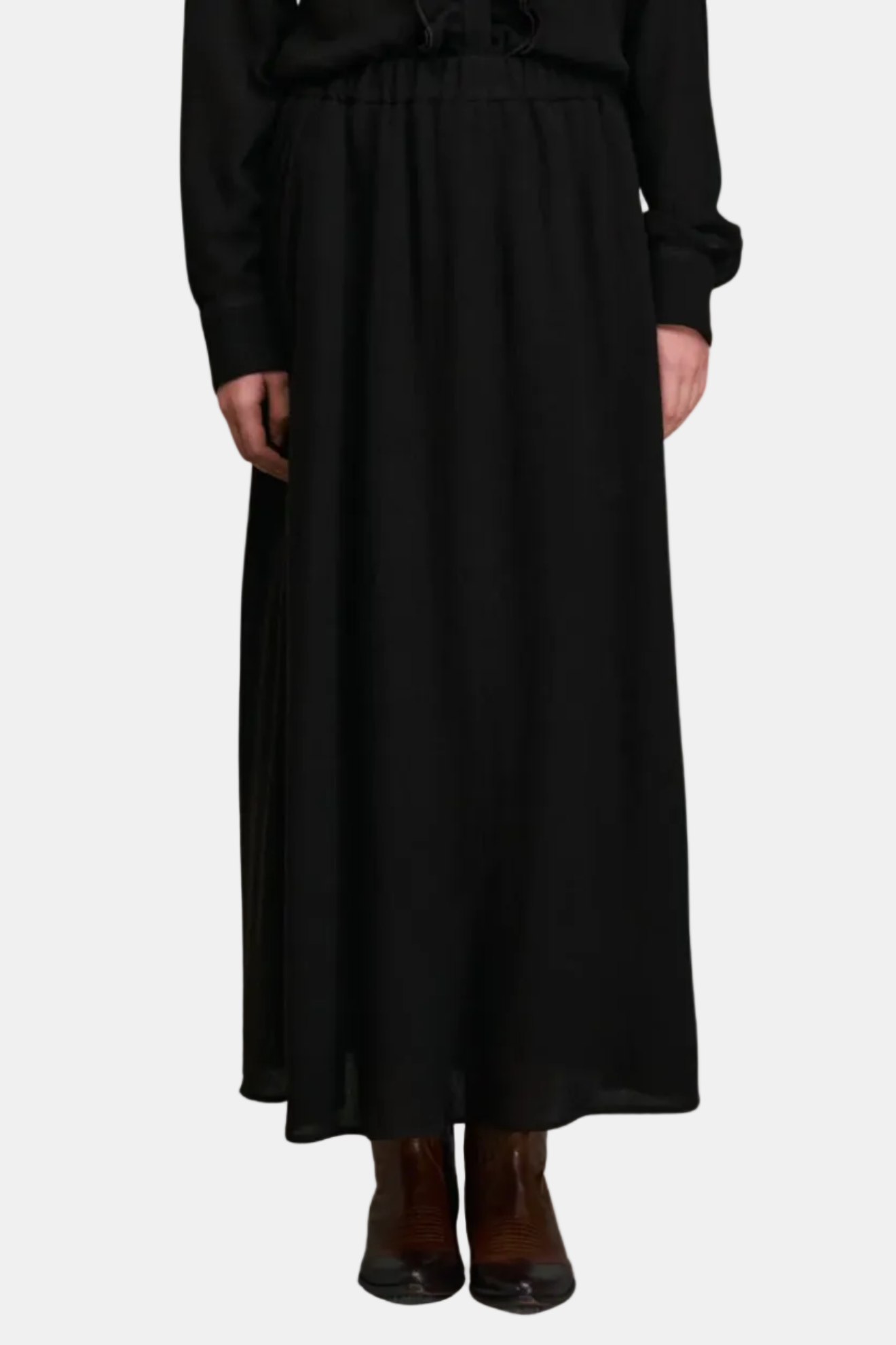 Person wearing a long black skirt with a plain background