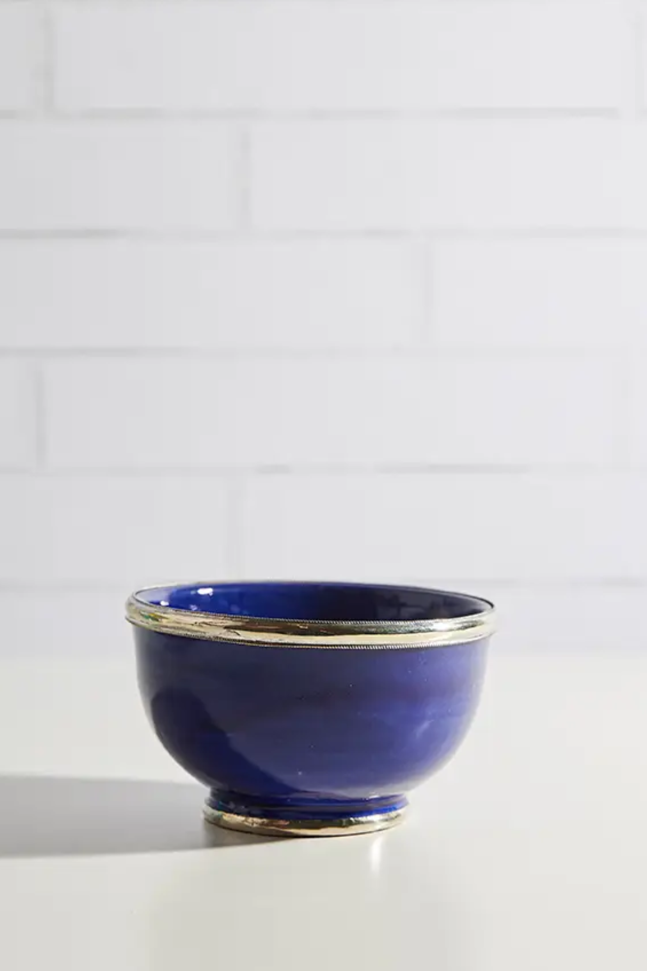 Blue ceramic bowl with silver rim on a white surface