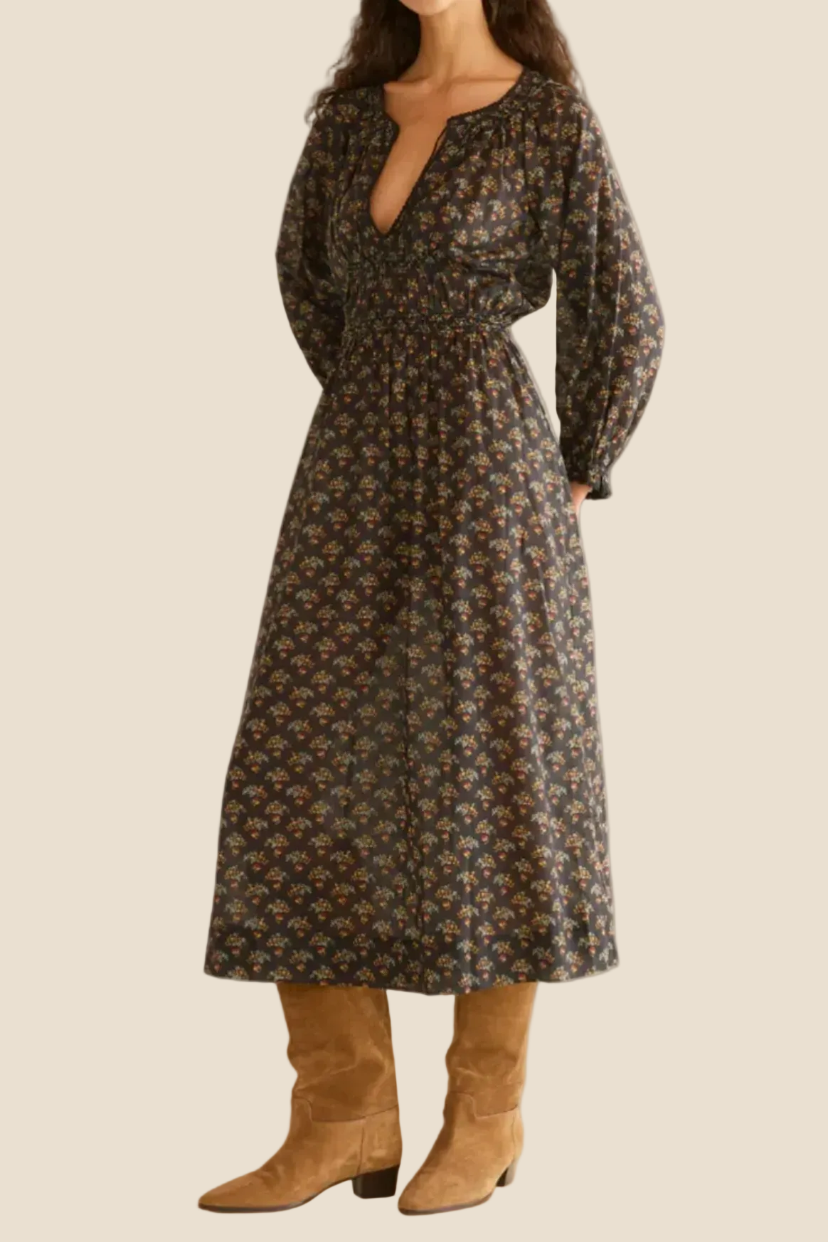 Woman wearing a floral dress with long sleeves and a belt, standing against a white background.