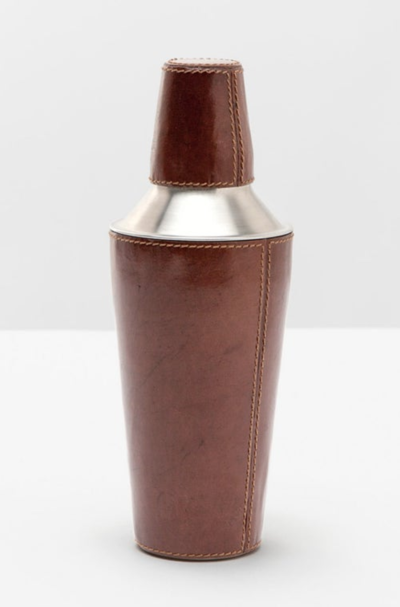 Brown leather cocktail shaker with silver top on a white background