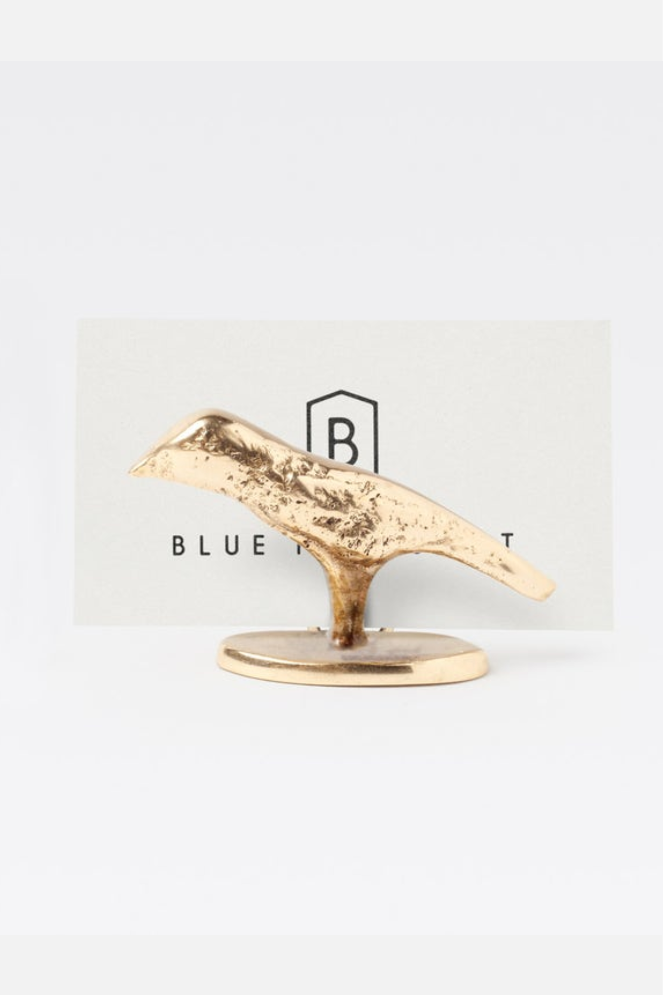Gold bird-shaped object on a white background with 'Blue Bottle' branding.