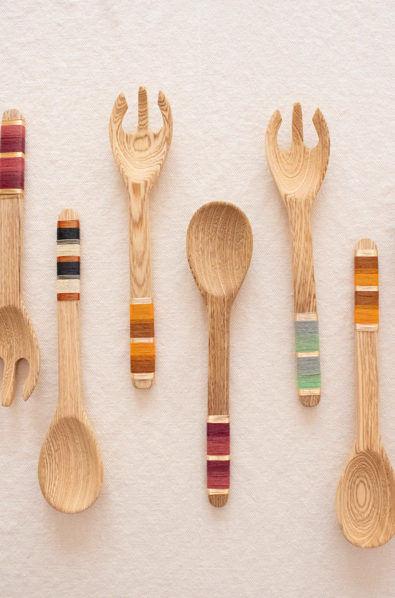 Set of wooden utensils with colorful handles on a light background