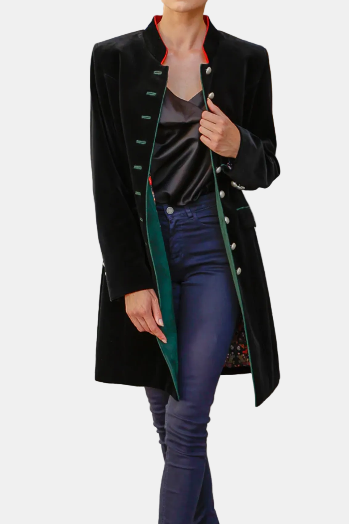 Woman in a black coat with green accents walking on a cobblestone street.