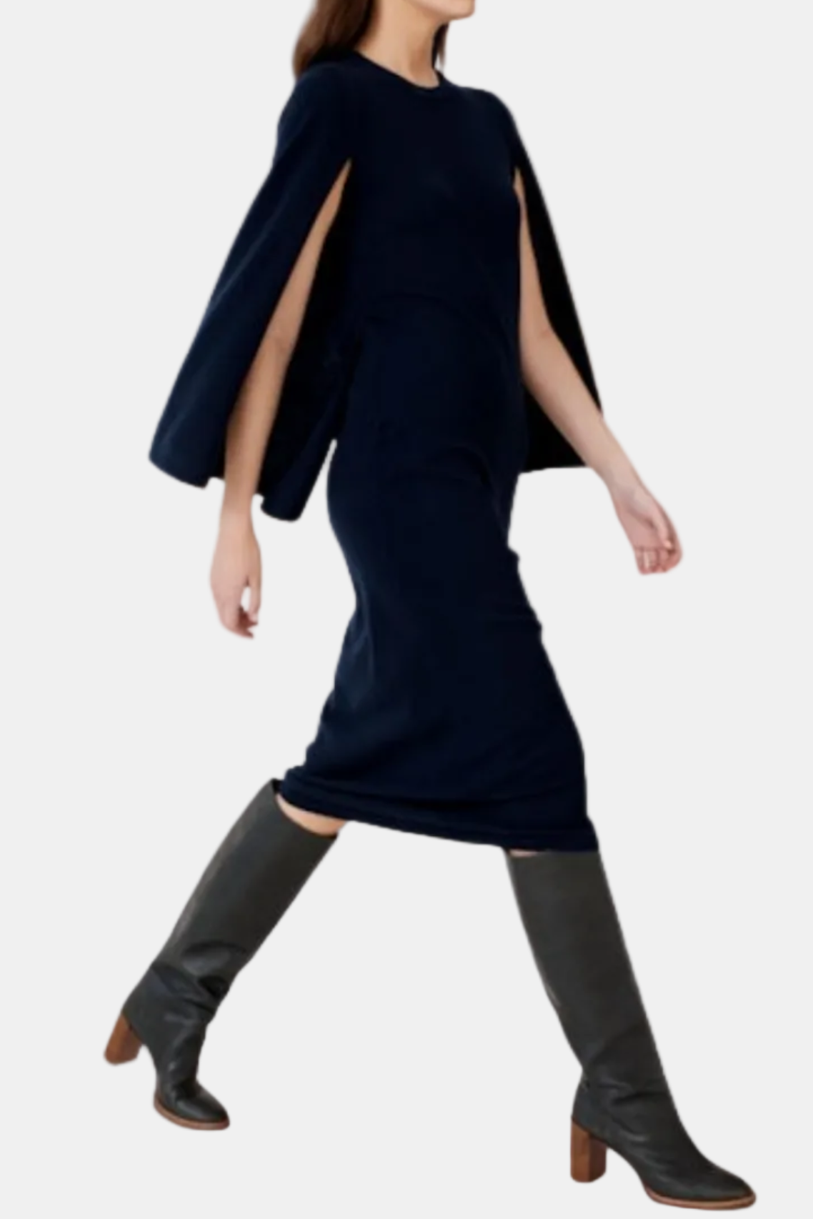 A woman modeling a dark navy blue dress with a cape-like draped sleeve and side slit, paired with dark gray knee-high heeled boots, against a plain white background.
