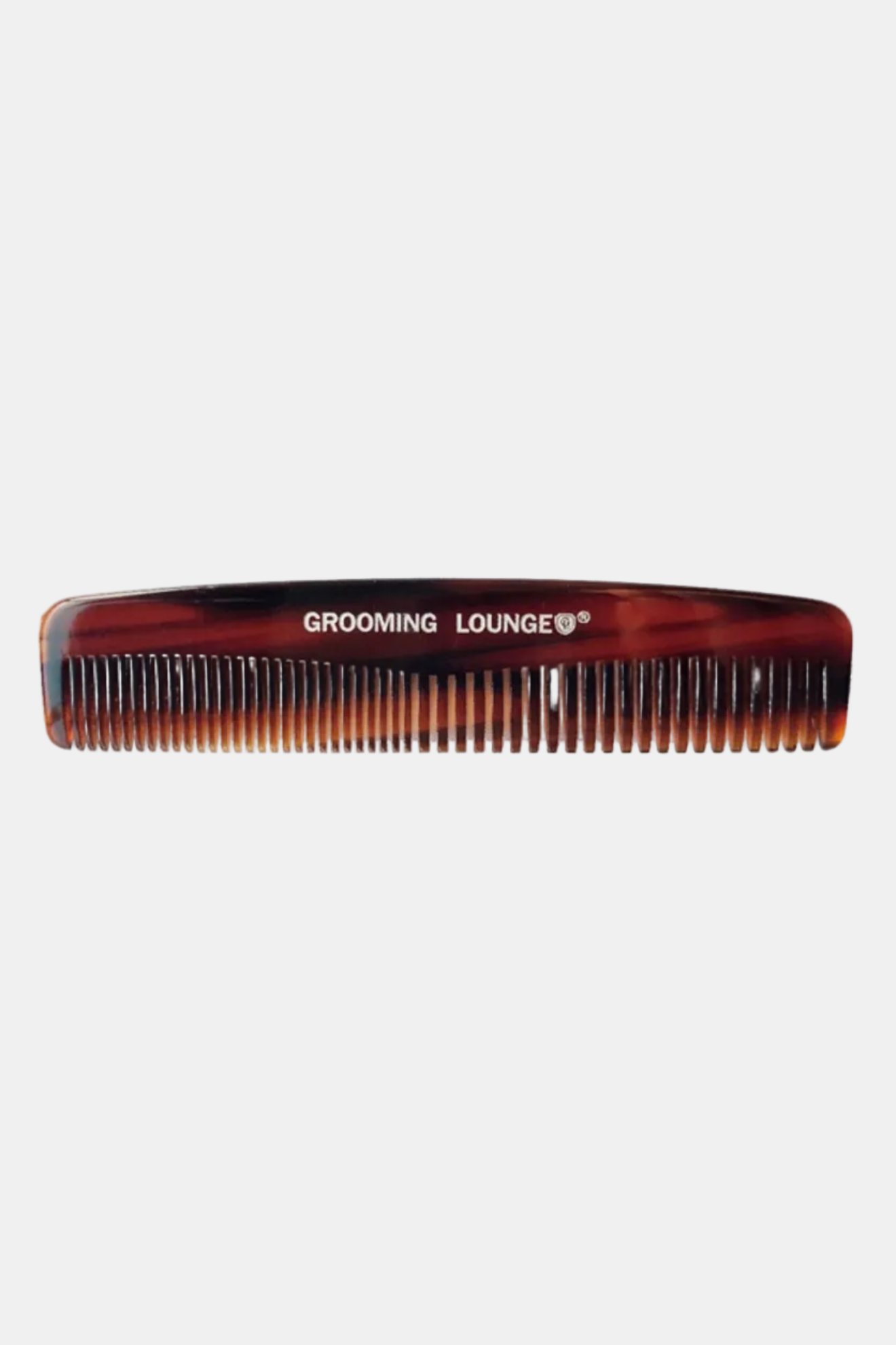 Tortoiseshell comb with 'Grooming Lounge' branding on a white background