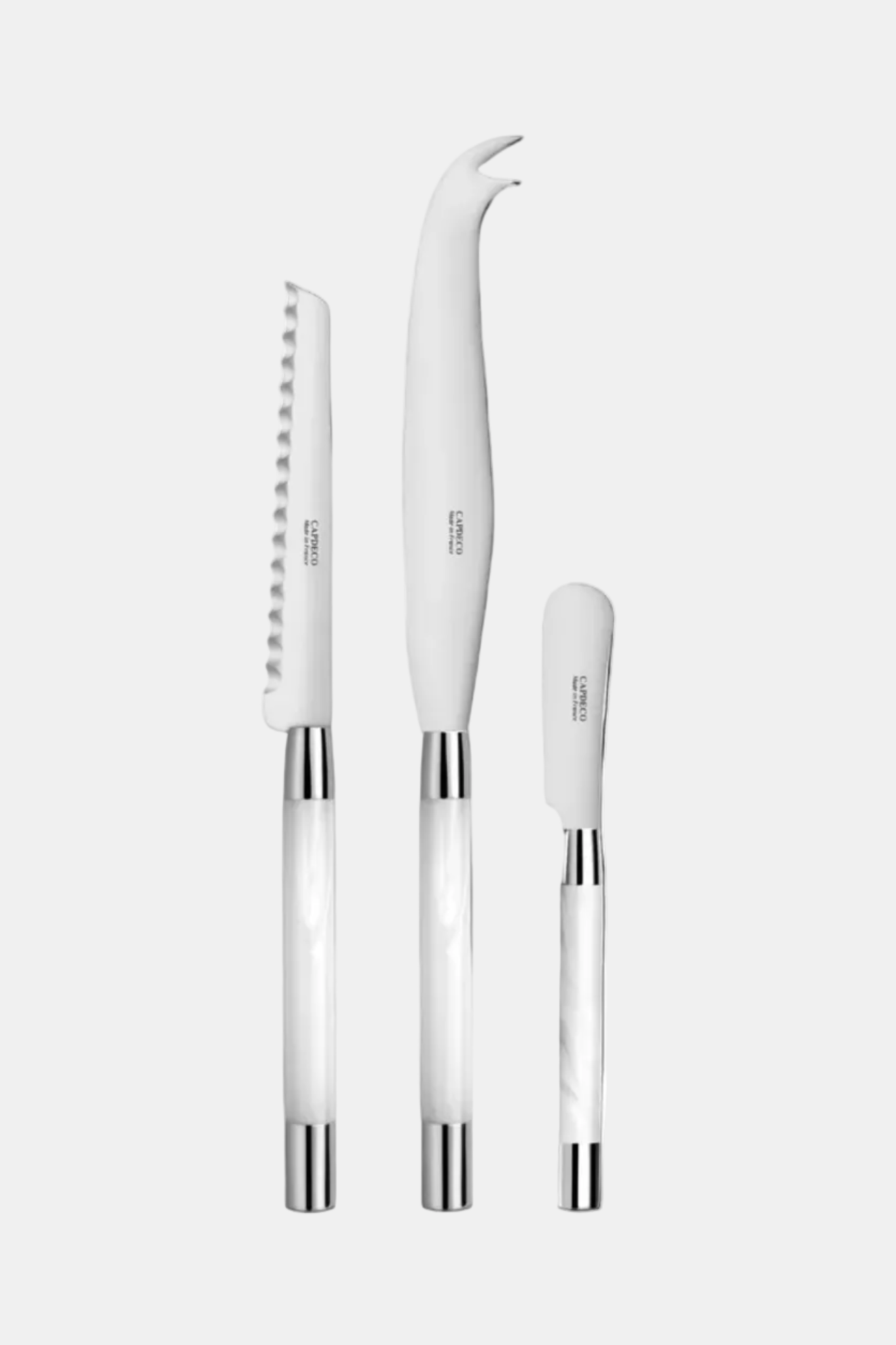 Set of three white kitchen knives with silver handles on a white background