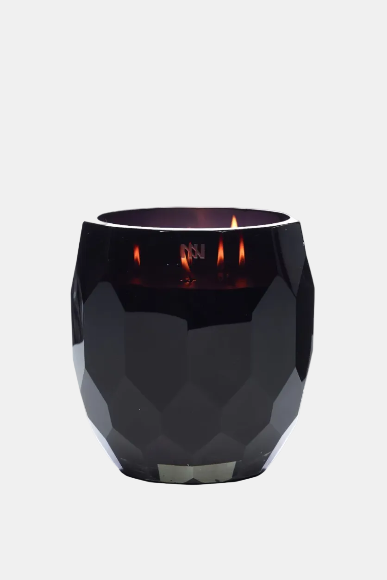 Black faceted candle holder with a lit candle on a white background