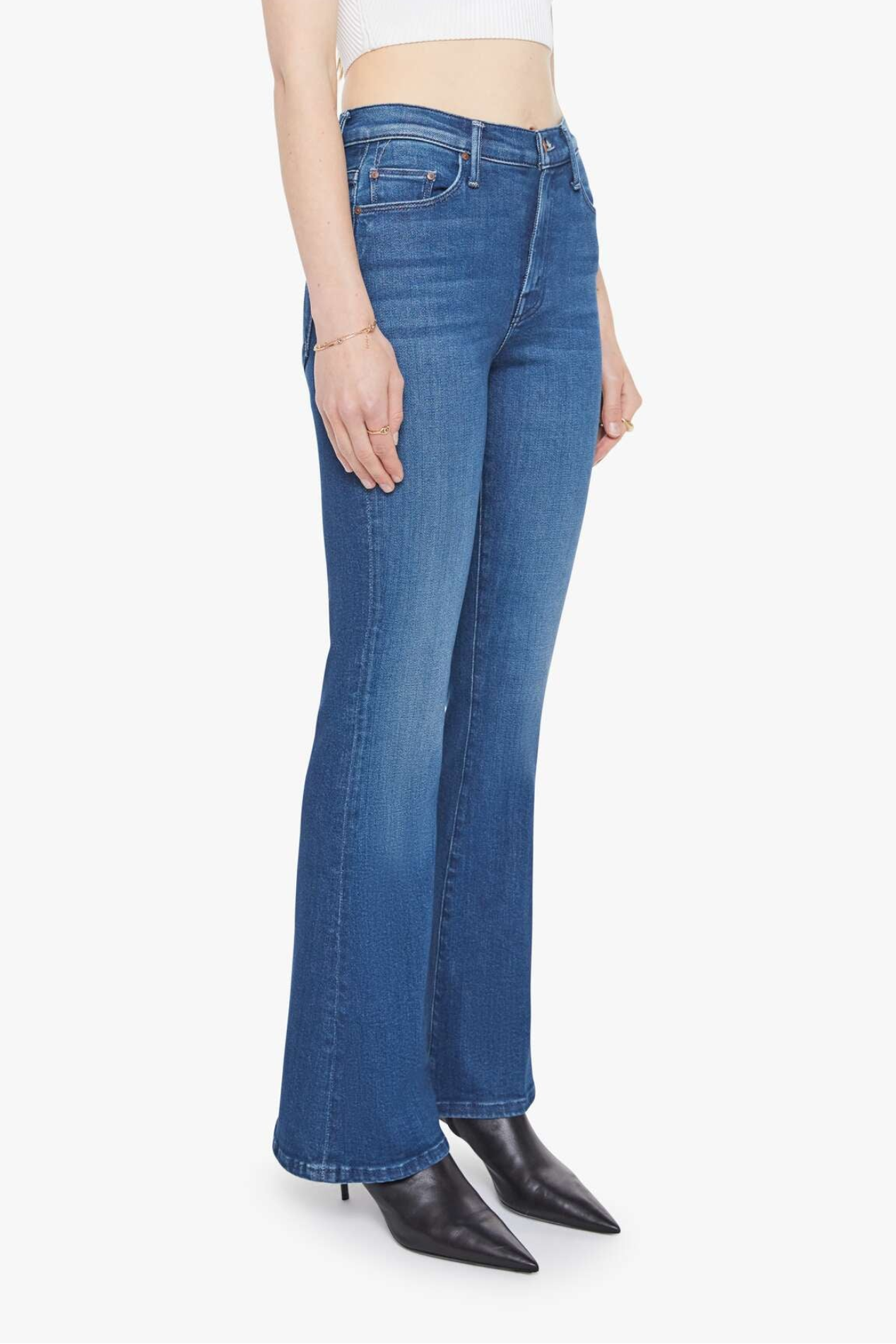 Person wearing blue jeans and black shoes on a white background
