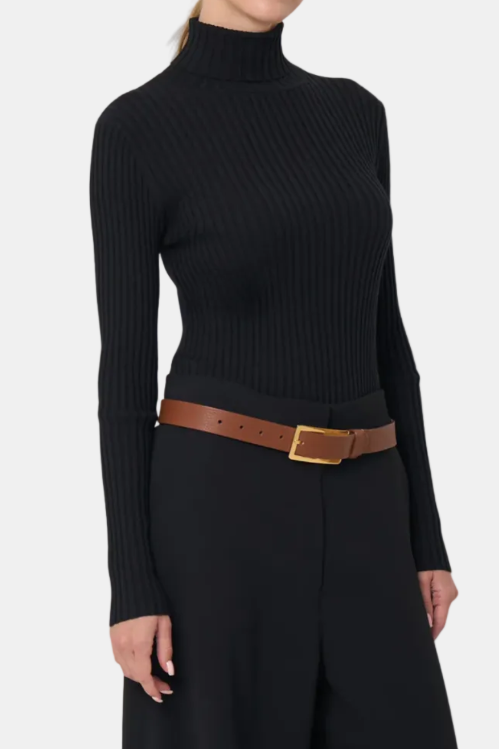 Woman wearing a black ribbed turtleneck sweater with a brown belt on a white background