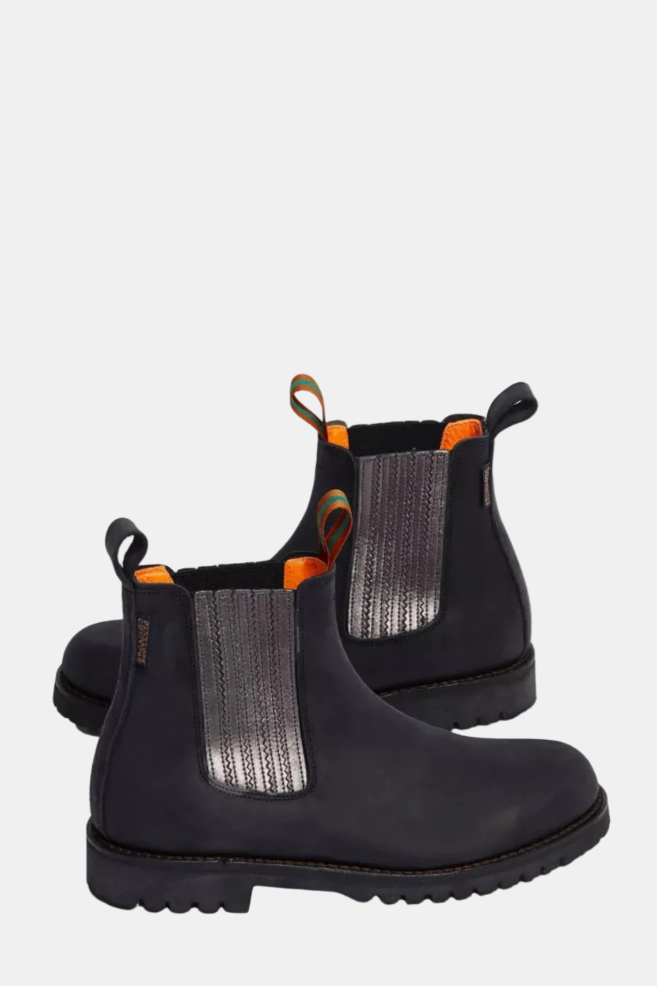 Pair of black Chelsea boots with orange accents on a white background