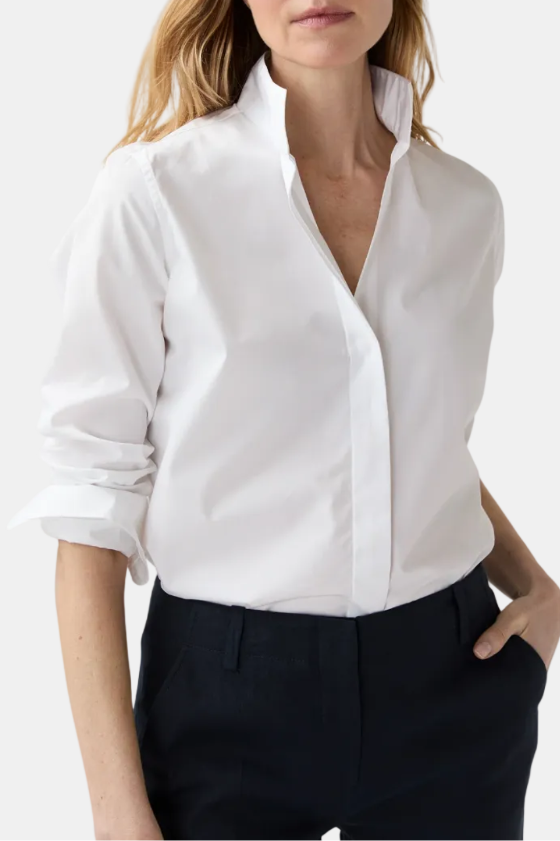 Woman wearing a white blouse and dark pants on a white background