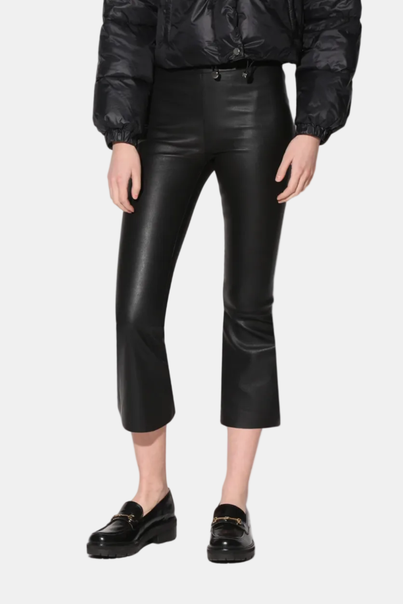 A pair of black Luisa Pant crop flare silhouette leather pants with a model standing against a white background.