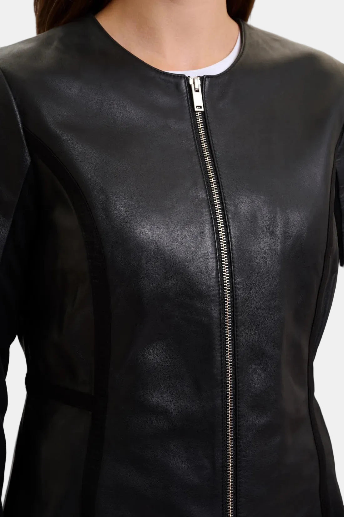 Close-up of a black leather jacket with a front zipper, worn by a model.