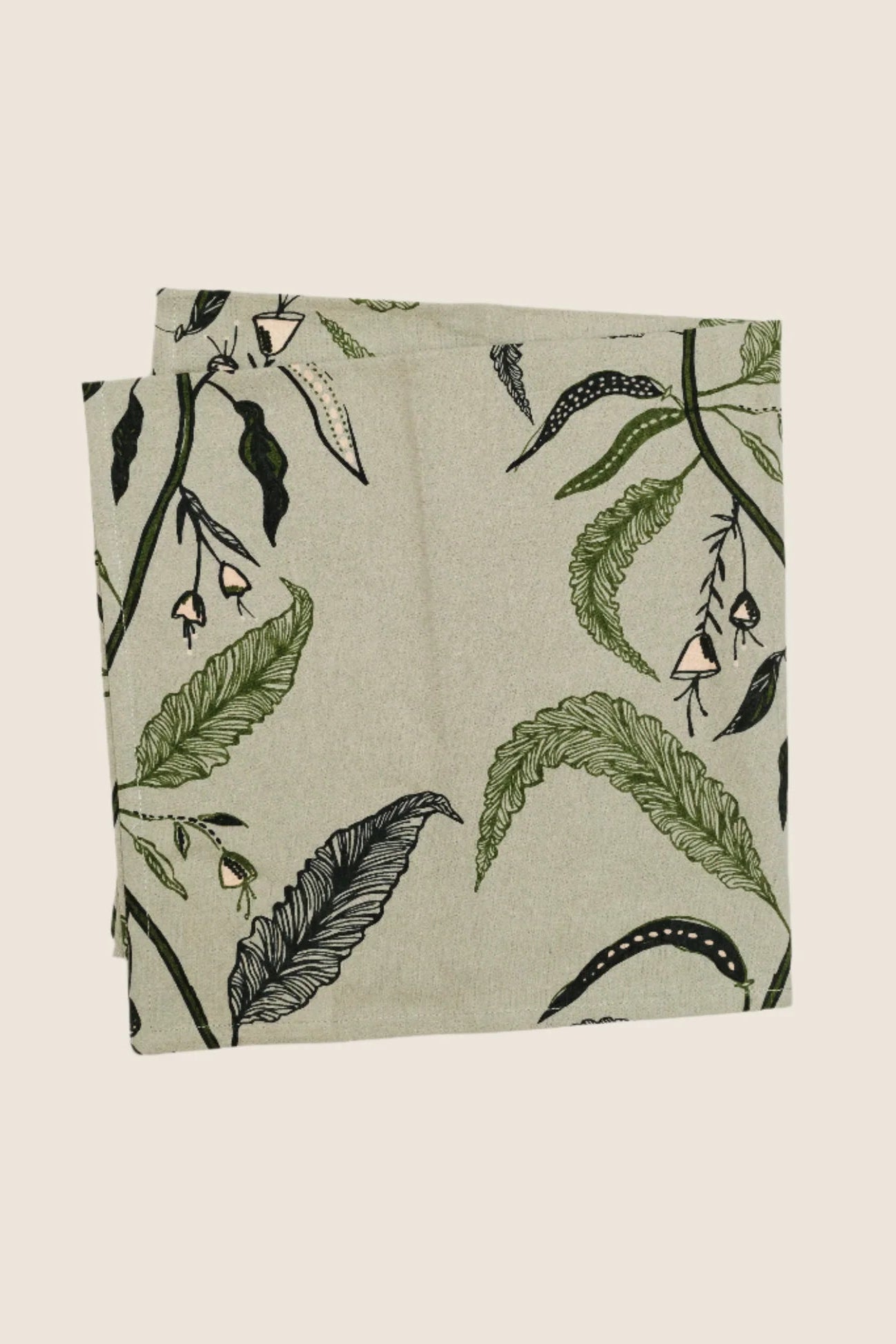 Two folded fabric swatches with green leaf pattern on a beige background