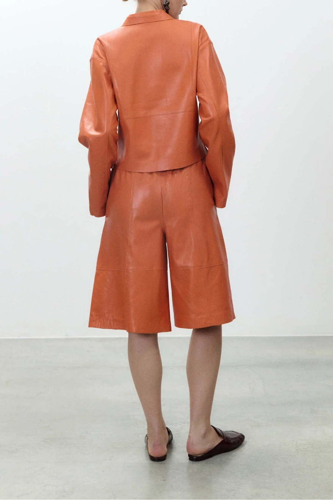 Person wearing an orange leather suit standing against a white background
