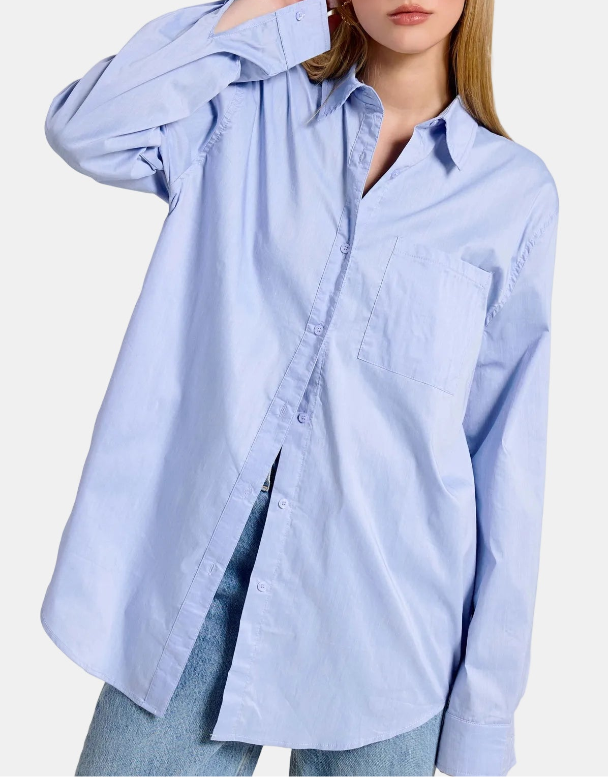 Woman wearing a light blue oversized shirt with a blurred background