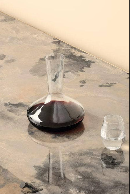 Wine glasses and a decanter with red wine on a textured surface