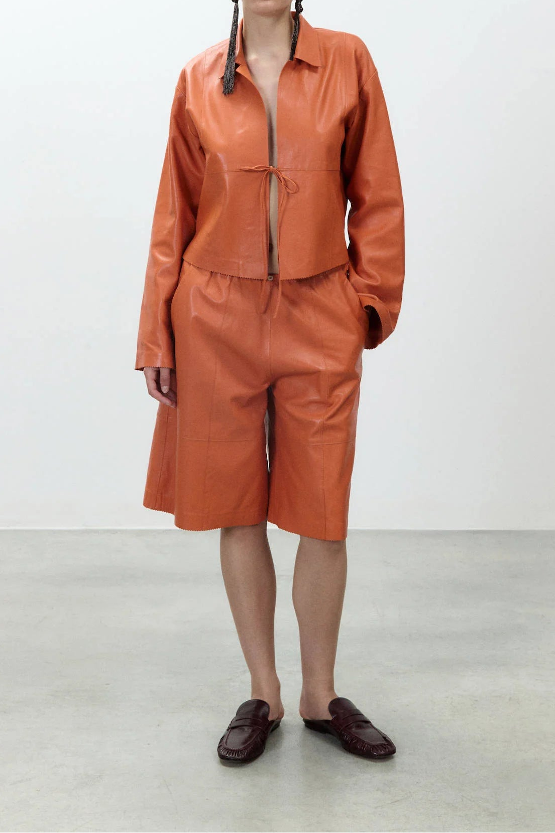 Person wearing an orange leather outfit on a plain background