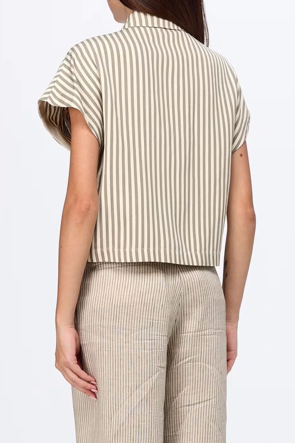 A model shown from the back wearing a short-sleeve collared shirt and matching striped trousers in beige and brown.