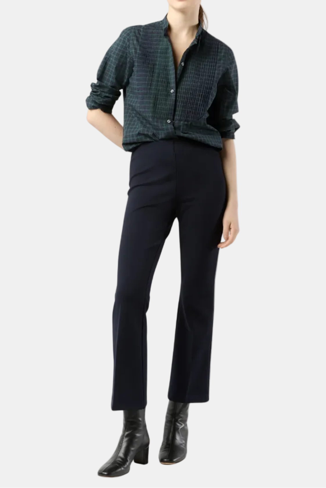 Woman wearing a dark green checkered shirt and black pants on a white background