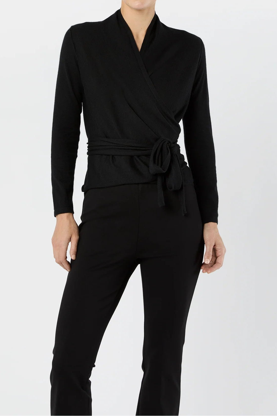 Woman wearing a black wrap top and pants on a white background