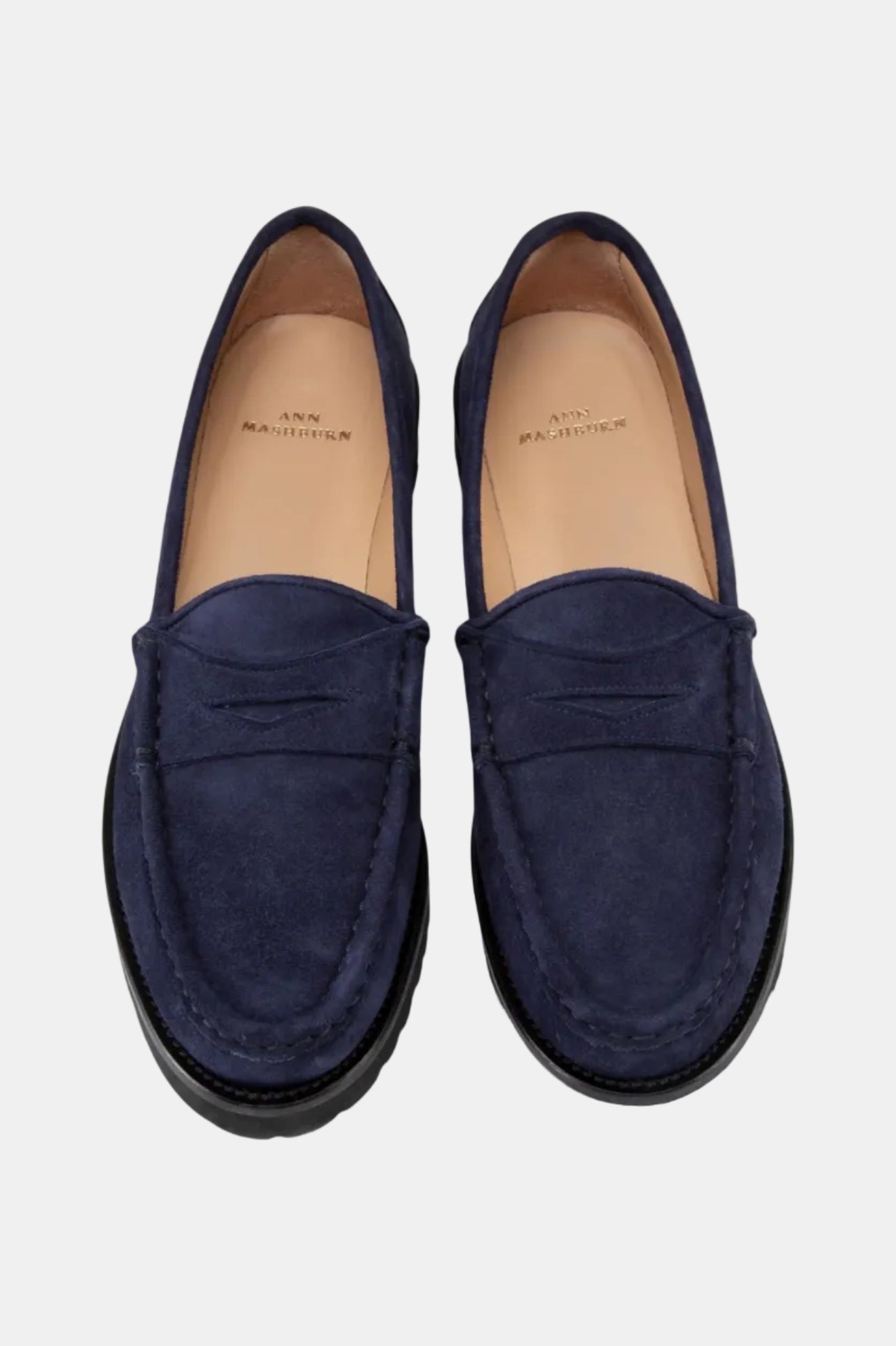 A pair of navy blue suede loafers with a lug sole.